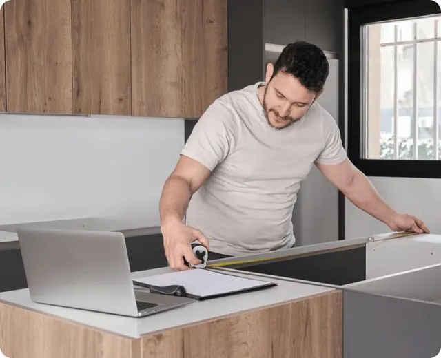 Contractor measuring kitchen cabinets on site